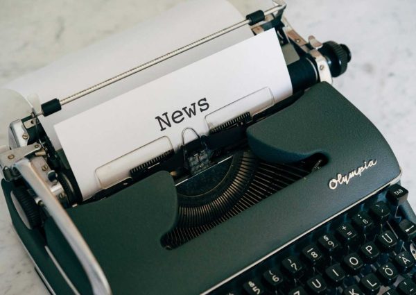 Close-up of an antique typewriter with 'News' on paper.